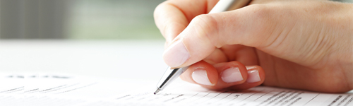 Image of person writing holding a pen.